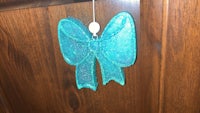 a blue glitter bow hanging on a wooden door