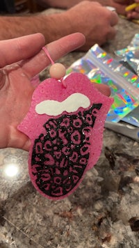 a person is holding a pink and leopard shaped ornament