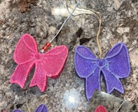 two pink and purple bows hanging on a marble countertop